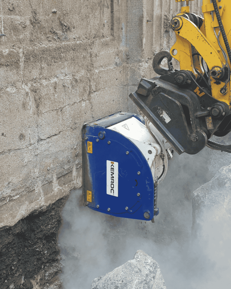 KEMROC EX patch planer carving deep slot alongside concrete retaining wall for utility trenching—clean, vibration-free rock cutting
