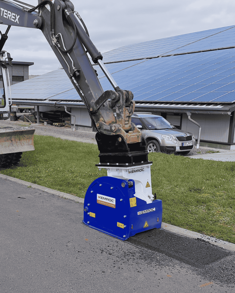 Compact KEMROC EX planer on excavator removes asphalt beside curb, creating precise patch for utility-service reinstatement