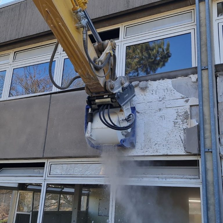 Excavator with KEMROC EX planer grinding vertical concrete wall—dust-controlled, low-vibration demolition solution